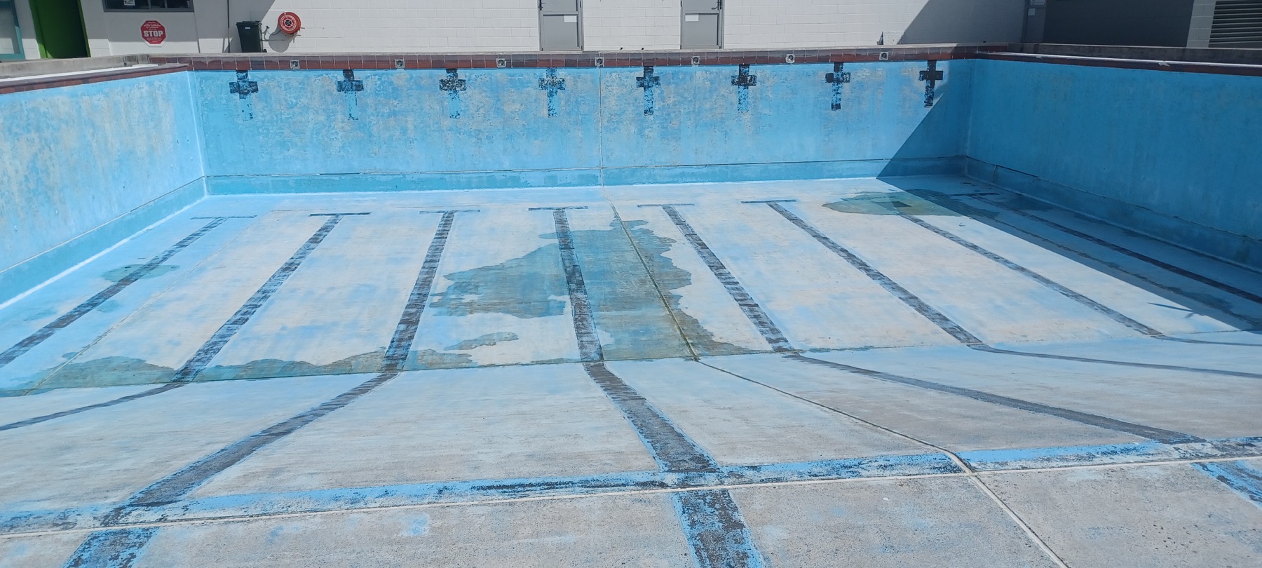 Before: worn blue commercial pool surface and faded lane markings.