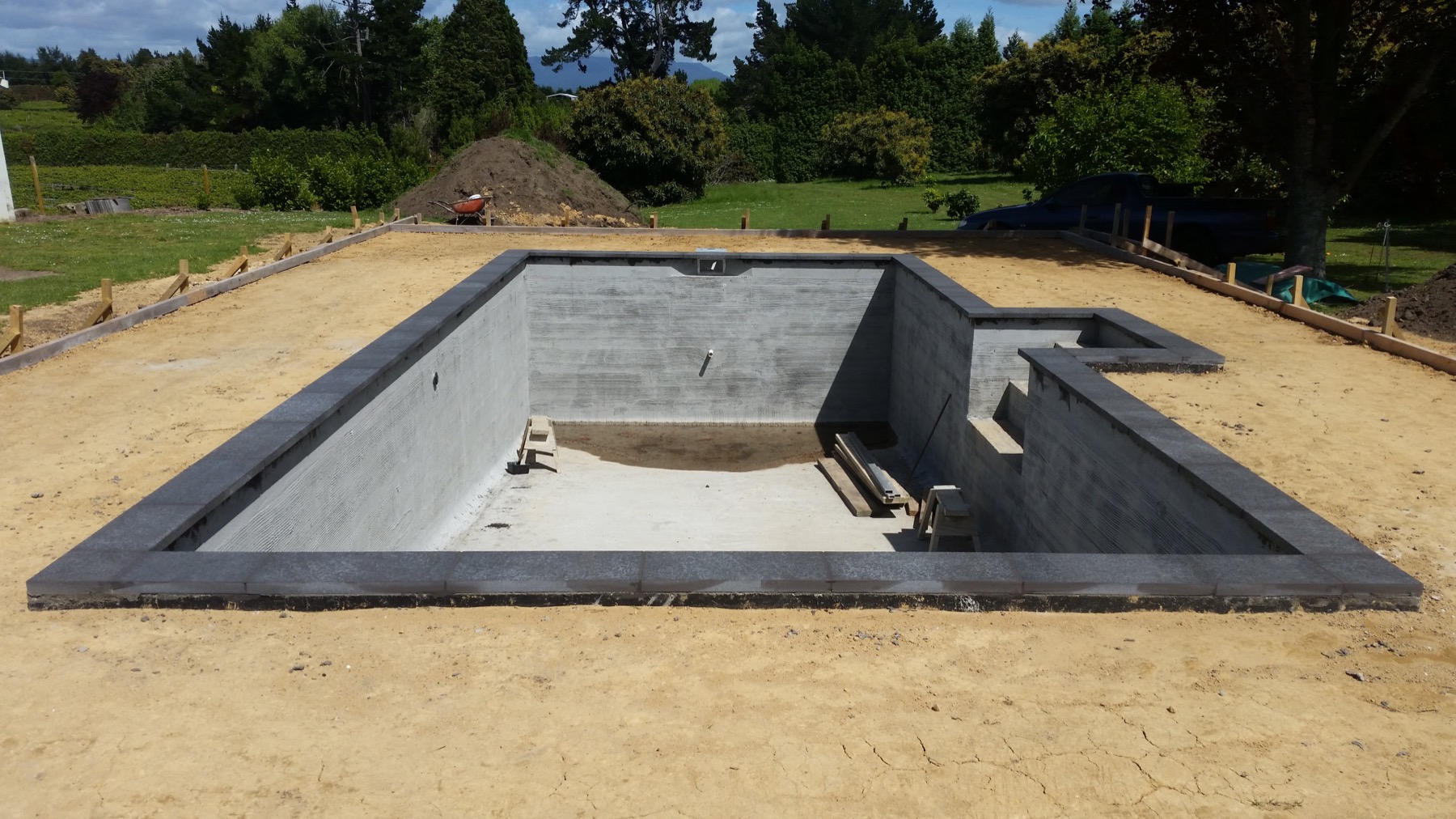 Concrete home pool under construction, with adjoining raised sections.